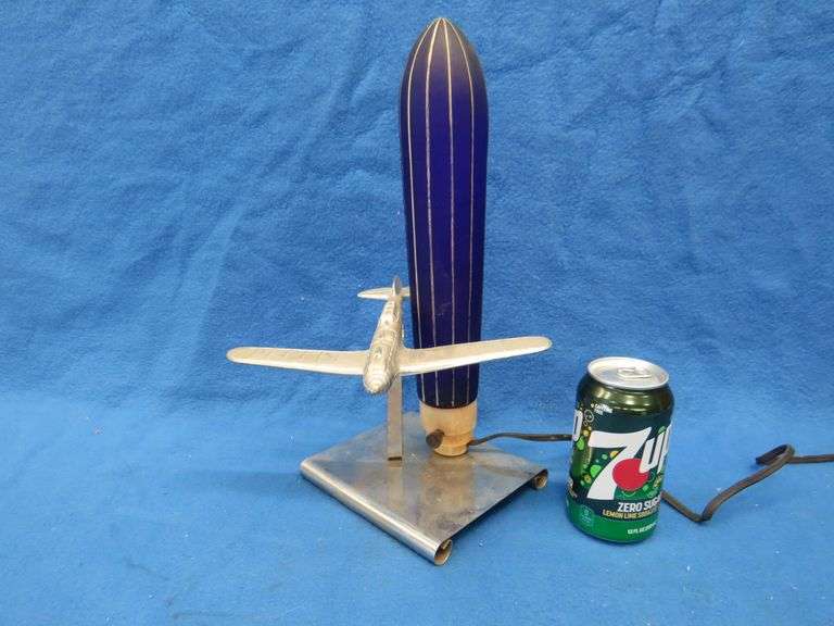 Art Deco era table lamp depicting an airplane in flight.  Cobalt blue glass shade