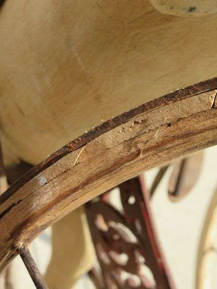 Antique wooden horse tricycle with a cast iron frame, hand-painted details, leather saddle, and wood
