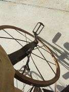 Antique wooden horse tricycle with a cast iron frame, hand-painted details, leather saddle, and wood