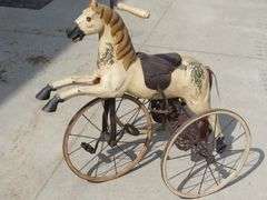 Antique wooden horse tricycle with a cast iron frame, hand-painted details, leather saddle, and wood