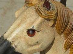 Antique wooden horse tricycle with a cast iron frame, hand-painted details, leather saddle, and wood
