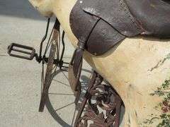 Antique wooden horse tricycle with a cast iron frame, hand-painted details, leather saddle, and wood