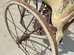 Antique wooden horse tricycle with a cast iron frame, hand-painted details, leather saddle, and wood