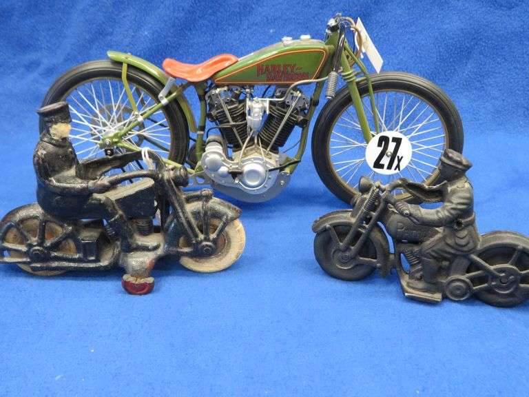Two vintage cast iron motorcycles, one with rubber tires, and a metal Harley-Davidson