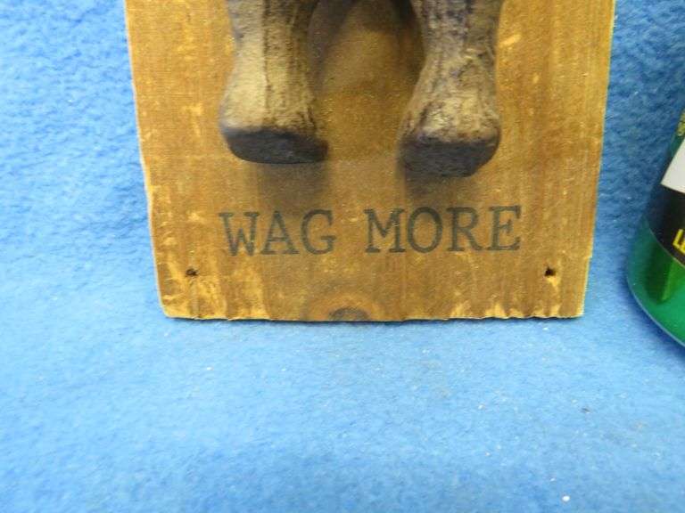 Cast iron south end of a dog going north on a wooden plaque