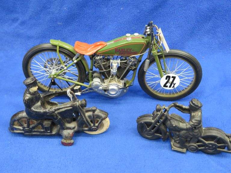 Two vintage cast iron motorcycles, one with rubber tires, and a metal Harley-Davidson