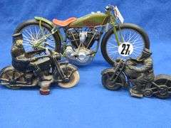 Two vintage cast iron motorcycles, one with rubber tires, and a metal Harley-Davidson