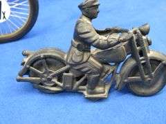 Two vintage cast iron motorcycles, one with rubber tires, and a metal Harley-Davidson