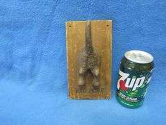 Cast iron south end of a dog going north on a wooden plaque
