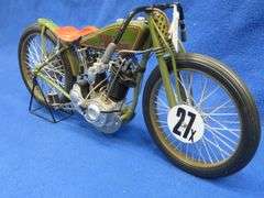 Two vintage cast iron motorcycles, one with rubber tires, and a metal Harley-Davidson