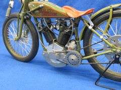 Two vintage cast iron motorcycles, one with rubber tires, and a metal Harley-Davidson