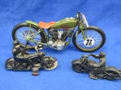 Two vintage cast iron motorcycles, one with rubber tires, and a metal Harley-Davidson