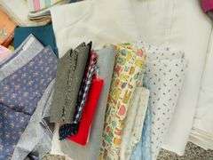 Large box of sewing material. Bolts of cloth. Curtains.