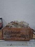 Vintage wooden CA grapes crate full of a variety of glass jars. 1e