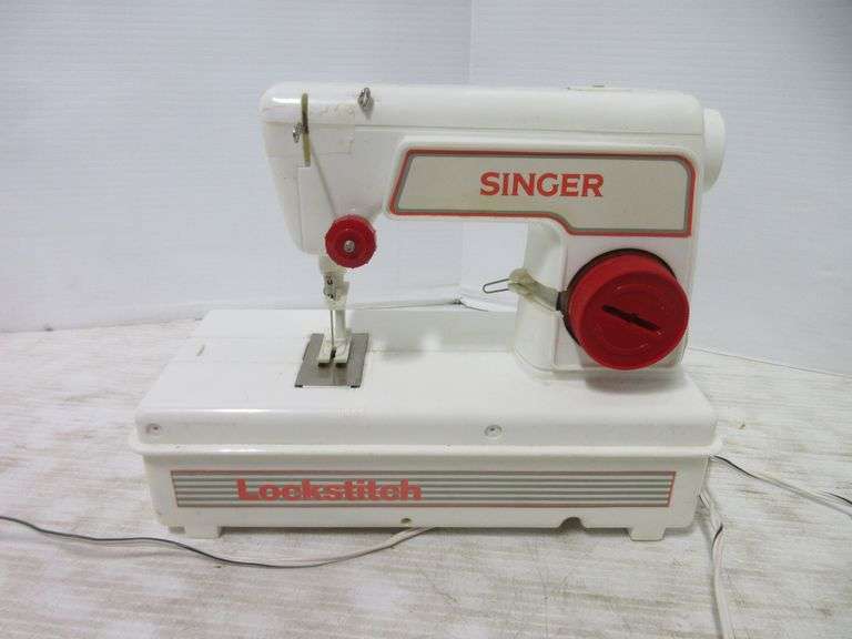 Red and white Singer toy sewing machine, wheel brings needle up and down, spool for thread is