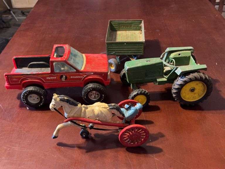 Vintage Toy Vehicles Including Red Truck, Green Tractor with Trailer, and Horse-Drawn Cart