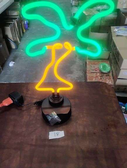 LED Neon Palm Tree Desk Lamp. This is a vibrant LED neon light shaped like a tropical palm tree, designed to provide decorative illumination for a desk or tabletop. - $45.00