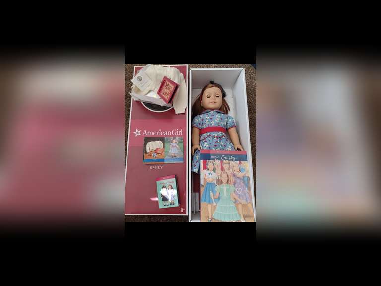 Emily Bennett. Emily is an original American Girl Doll. She stands 18 inches tall and wears her original period clothing. She is the best friend of Molly McIntire. Her time-period is World War II England. Emily has been displayed exclusively behind glass in a smoke-free environment, and she has not been used for play.
Emily comes complete with all her accessories in her original box, including her doll stand and her book, “Brave Emily”