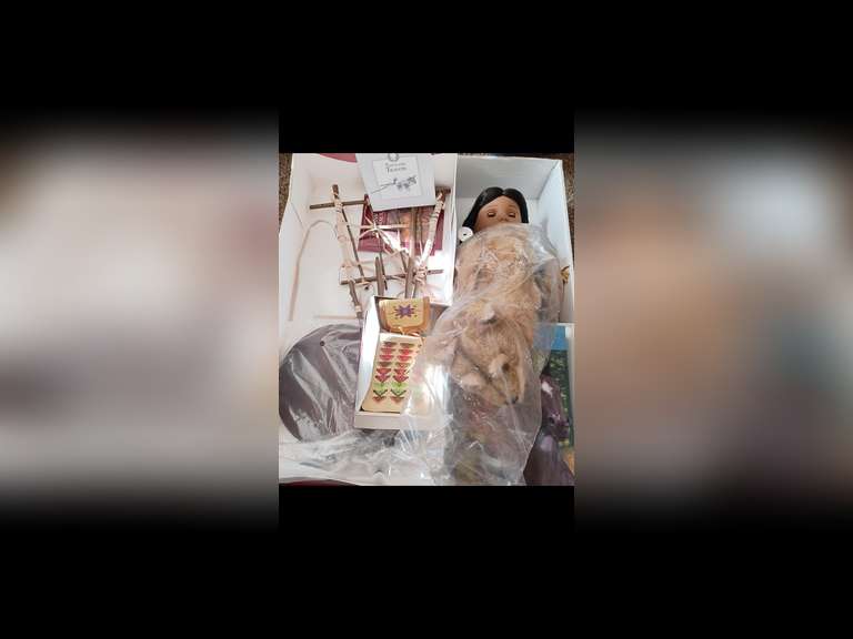 Kaya is an original American Girl Doll. She stands 18 inches tall and wears her original period clothing. Kaya is a Nez Perce girl Her time-period is the 1760s in the Pacific Northwest.
Kaya has been displayed exclusively behind glass in a smoke-free environment, and she has not been used for play.
Kaya comes with her handbag and wallet, along with her book, “Kaya, The Journey Begins” in the original box. Her doll stand, travois with wolf dog, Tatlo are packed in a separate box.