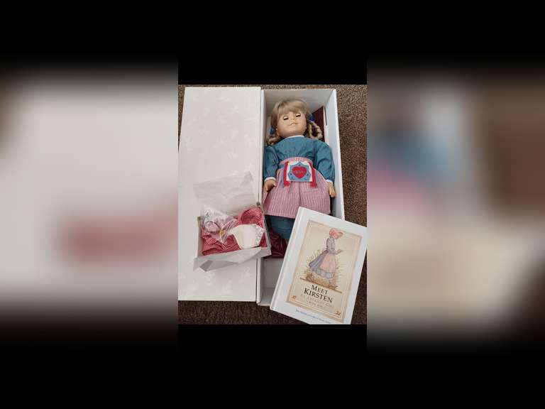 Kirsten Larson. Kirsten is one of Pleasant Company’s original first-four American Girl Dolls. She stands 18 inches tall and wears her original period clothing. She represents life in the mid-1800s as a Swedish immigrant on a Minnesota farmstead. Kirsten has been maintained exclusively for display behind glass in a smoke- free environment and she has not been used for play.
Kirsten come with her accessories in her original box, including doll stand and her book, “Meet Kirsten”.