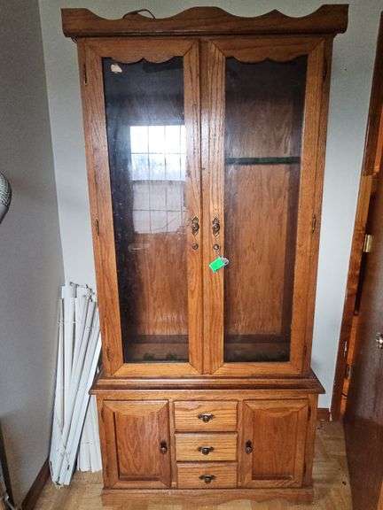 Solid oak gun cabinet with glass doors and a lower storage area with drawers