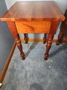 Vintage cherry wood nightstand with a single drawer and turned legs.