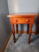 Vintage cherry wood nightstand with a single drawer and turned legs.