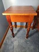 Vintage cherry wood nightstand with a single drawer and turned legs.