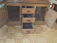 Solid oak gun cabinet with glass doors and a lower storage area with drawers