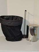 Close tote, toilet paper holder, & metal trash can.