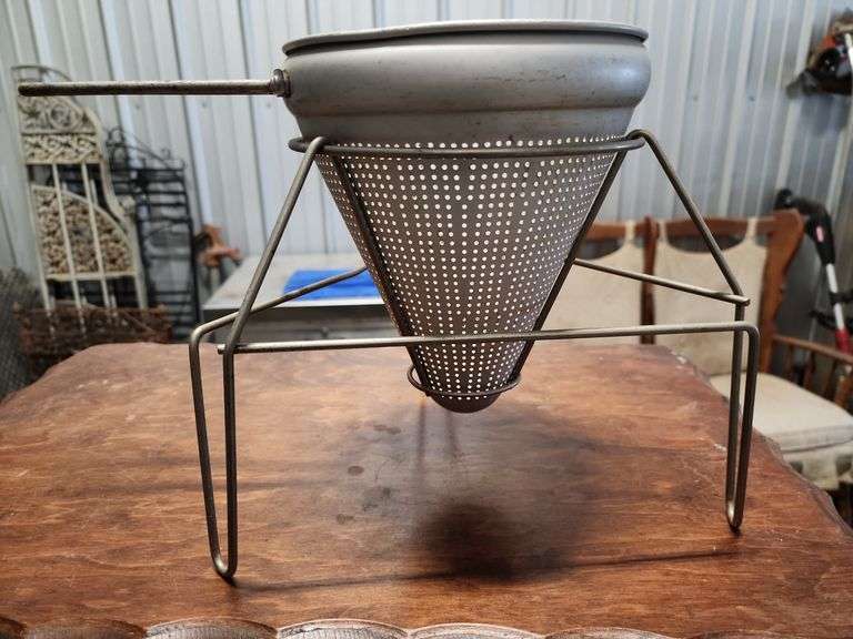 vintage aluminum cone strainer with a metal stand and wooden pestle