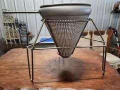 vintage aluminum cone strainer with a metal stand and wooden pestle