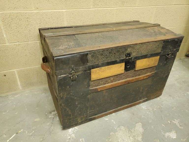 Antique wood and metal steamer trunk features floral metal work on lid top (still shows a little red color) (±((, casters on bottom, leather handles are still in good condition. Measures 32 in W X 18 in DX 21 in H.