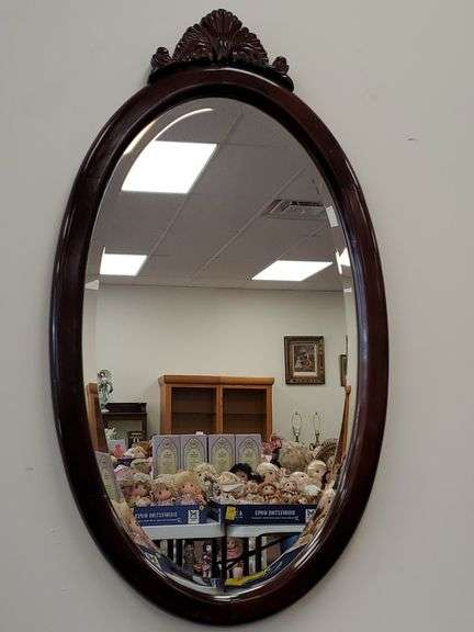 The Bombay Company dark finish oval mirror with bevel edged glass and upper shell accent measures 34 in tall x19 in wide.