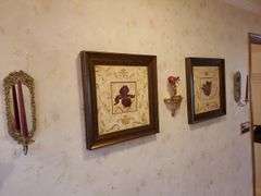 (2) mirrored brass candle sconces, 1 minerature wall shelf with figurine, and framed and matted floral art works by Laurel Lehman 20 in square. All for your bid! Master bathroom