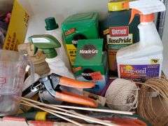 (2) shelf lot of gardening items including Miracle-Gro fertilizers, size 9 Garden Crocs, work gloves, planting pots, spring wreath, outdoor welcome flag. Garage