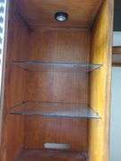 Beautiful solid wood entertainment center featuring beveled edged glass on doors, twisted metal accents in antique bronze finish, glass shelves with overhead lights, and plenty of storage, measures 108 in wide 24 in D X 74 in h. Breaks down into approximately five pieces. Family room.