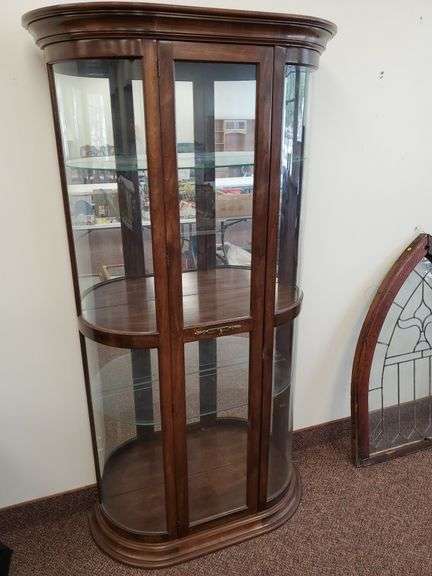 P. Reinisch Co. Curved glass and solid wood, upper and lower lighted shelves curio cabinet featuring two adjustable glass shelves with plate rails. Measures 27 in WX 16 in DX77 in H.