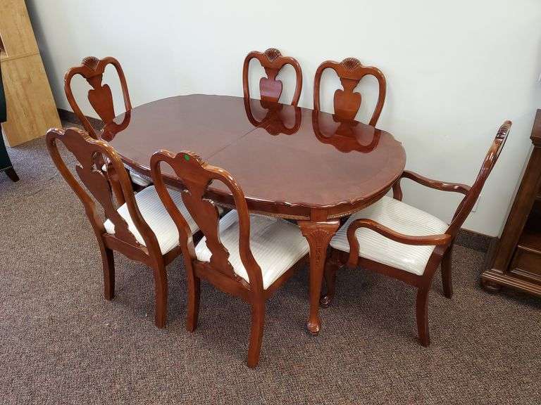 Queen Anne style dining table with inlaid wood top measures 62 w x 42 d x 30 H and features scalloped edge, accented table legs, (6) chairs (2) Captain's chairs, (4) dining chairs with stripped upholstered seats. Also includes covers for the table top.