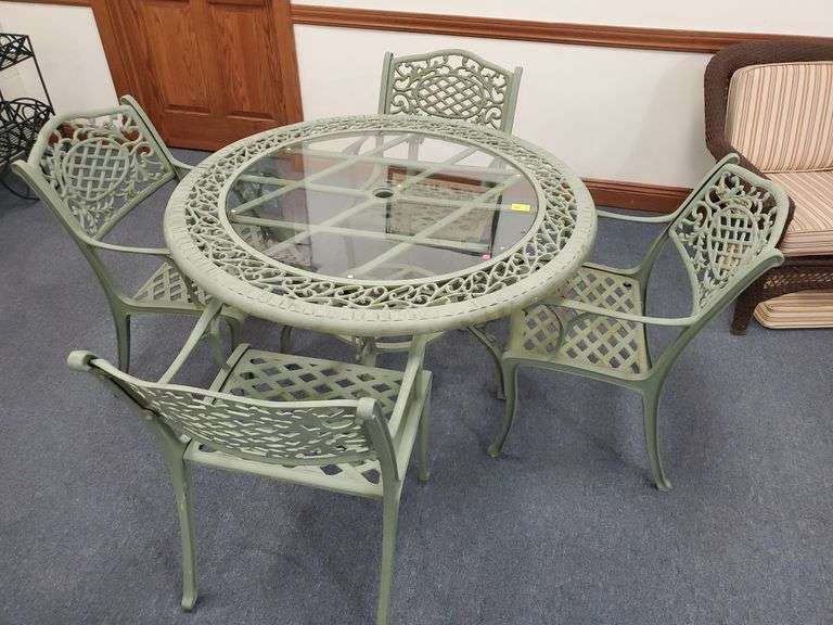 Cast Iron Patio Table with 4 Chairs and Glass Top with Umbrella Opening. Table Diameter is 48". Chairs and Table Feature Ornate Lattice Style Work