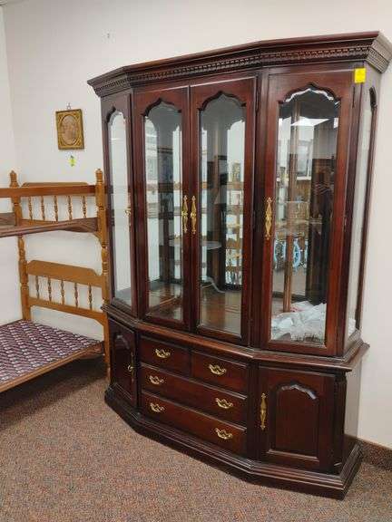 Thomasville solid wood two-piece china cabinet. Includes all glass shelves. Features lighted glass cabinet, beveled edge glass doors and mirrored back. Measures approximately 64 in w x 17 in D x 81 in H. Glass shelves are all wrapped in a tote.