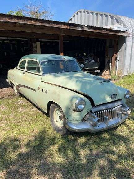 Light green 1952 Buick two-door sedan with straight-eight engine, parked under a pole barn