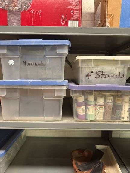 Four plastic totes, two empty, one with stencils, and one with paint supplies,
