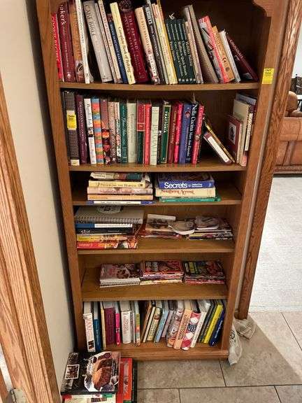 Contents of bookcase includes mainly cookbooks.