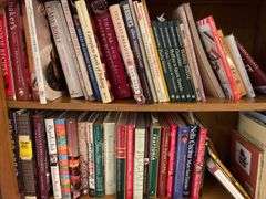 Contents of bookcase includes mainly cookbooks.