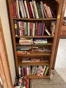Contents of bookcase includes mainly cookbooks.