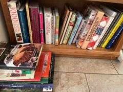 Contents of bookcase includes mainly cookbooks.