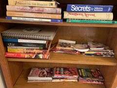 Contents of bookcase includes mainly cookbooks.