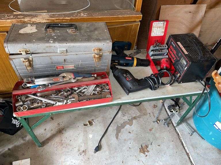 Table top of tools. Featuring battery charger. Drill. Toolbox in miscellaneous tools.