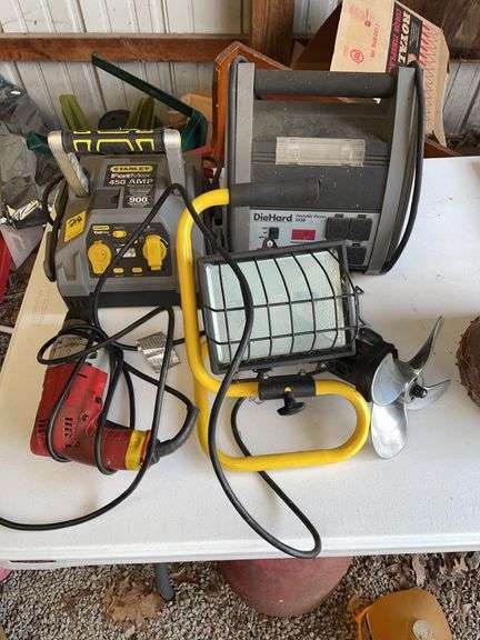 Pole barn. Two jumpstart boxes. A floodlight. Hitch cover of boat propeller in Milwaukee corded drill.